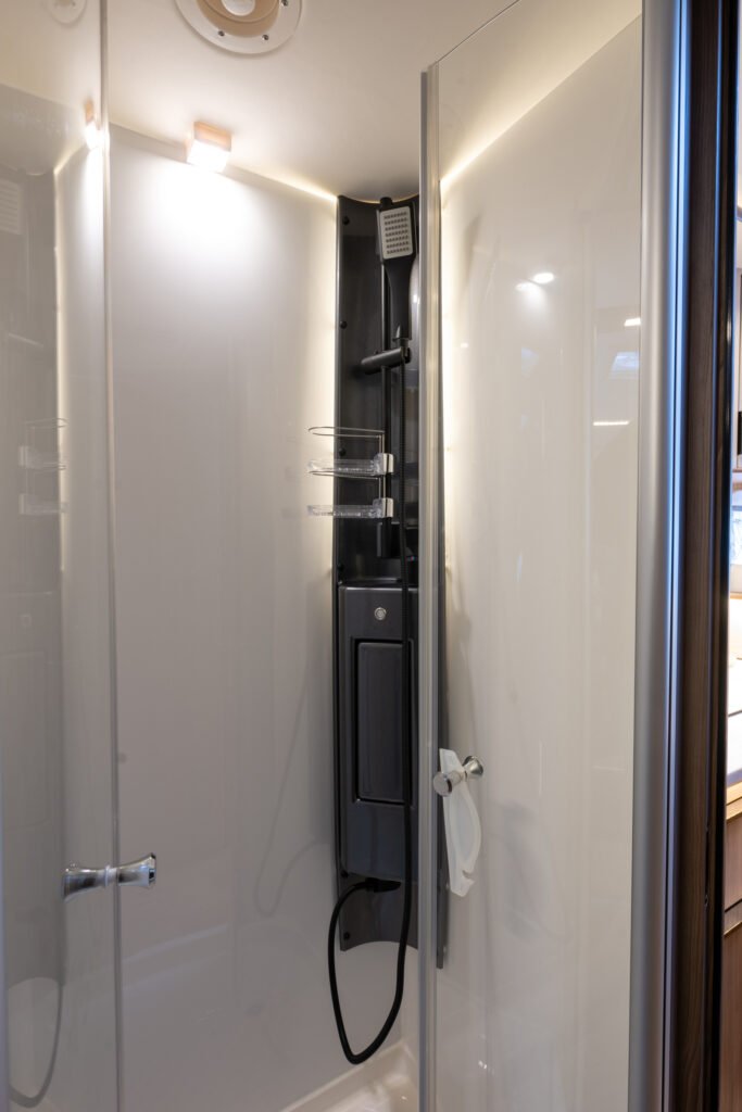 Obrázek zobrazuje moderní sprchový kout v obytném autě s elegantním designem.