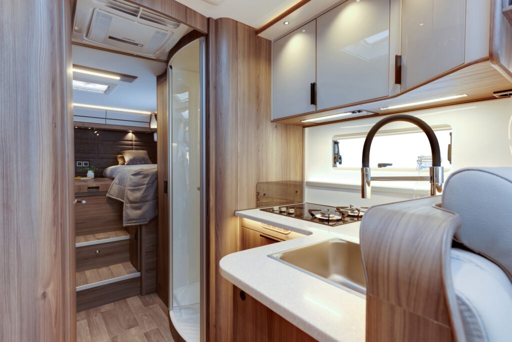 Interiér moderního obytného auta s kuchyní a ložnicí, elegantní design a pohodlné vybavení.