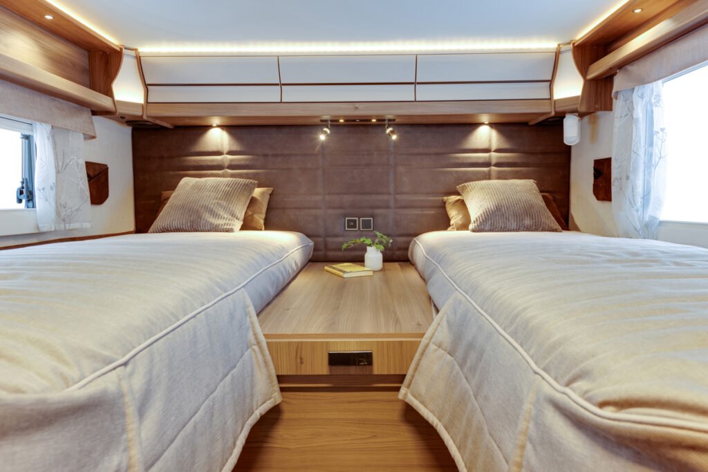 Luxusní interiér obytného auta s oddělenými lůžky a moderním osvětlením pro pohodlný odpočinek.