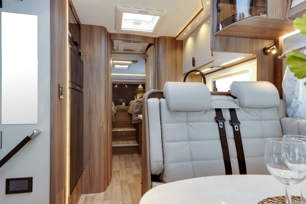 Interiér moderního obytného auta, elegantní design, dřevěné detaily a pohodlné sezení. Ideální pro cestování.