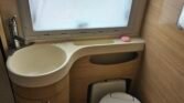 Koupelna v karavanu, praktické umyvadlo a toaleta, stylový interiér pro komfort na cestách.