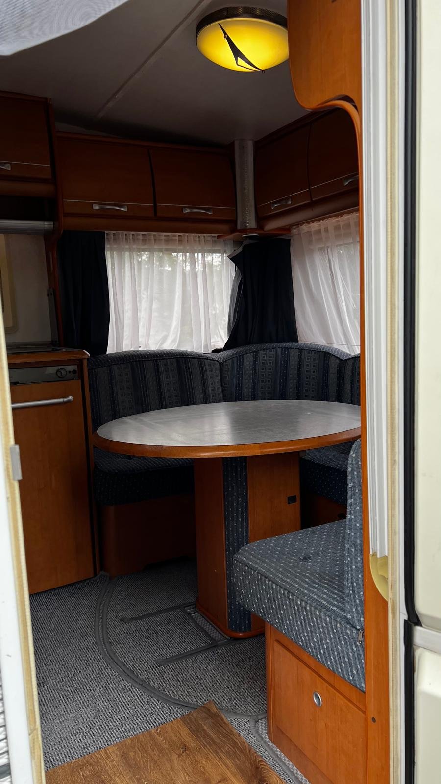 Interiér karavanu s útulnou jídelnou a pohodlným sezením. Ideální pro vaši cestu.