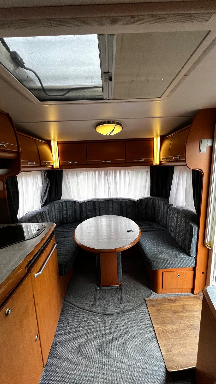 Karavan, moderní interiér s pohodlným sezením a stolem, ideální pro vaše dobrodružství.