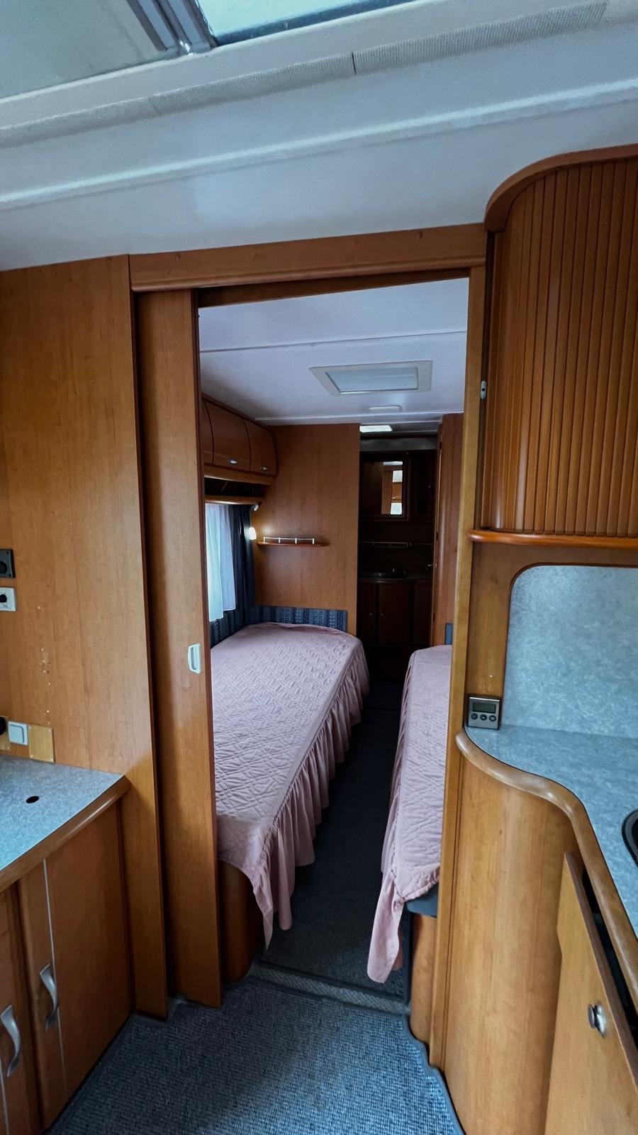 Interiér karavanu s pohodlnými lůžky a kuchyňským koutem. Ideální pro pohodlné cestování a rekreaci.