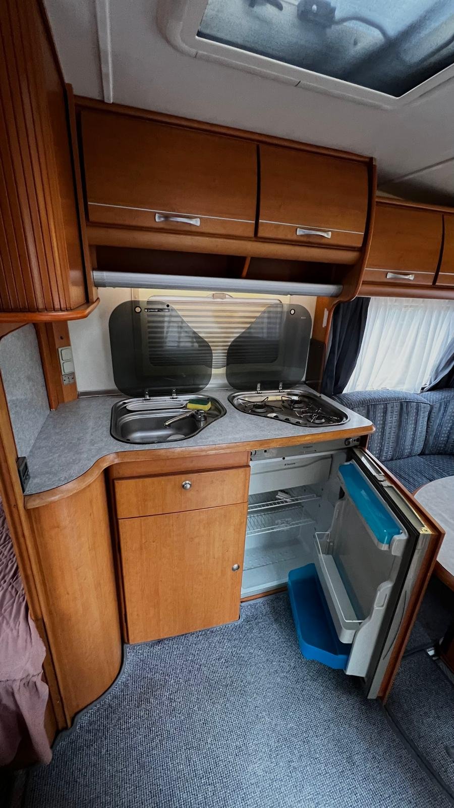 Kuchyňka v obytném autě, dobře vybavená s dřezem a plynovým sporákem. Ideální pro pohodlné vaření na cestách!