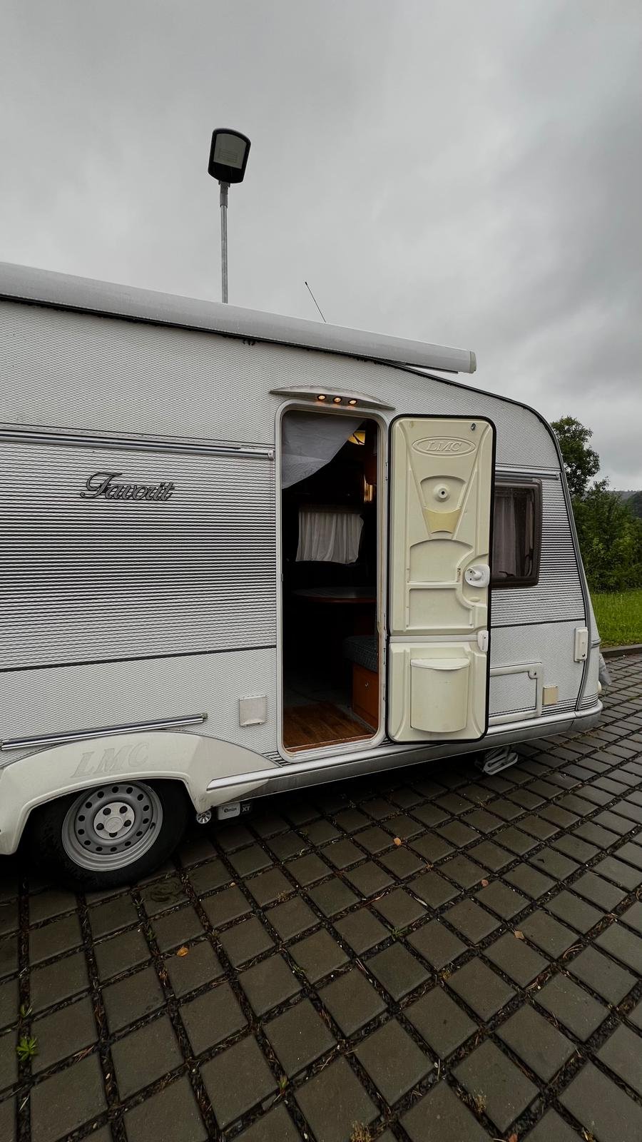 Karavan LMC s otevřenými dveřmi, připravený na dobrodružství. Ideální pro rodinné výlety a kempování.