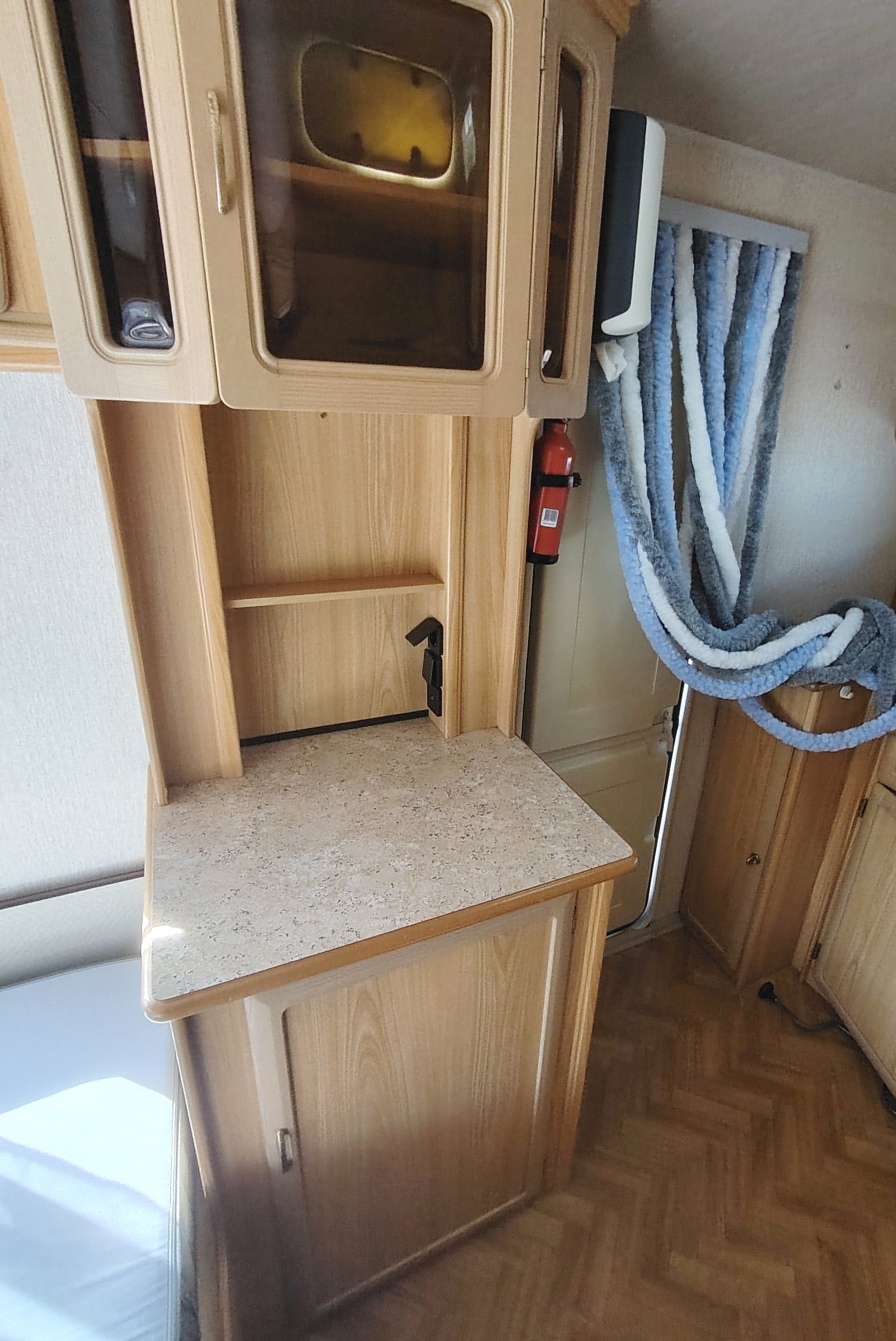 Interiér karavanu s dřevěnými skříňkami a kamenem na pracovním stole, ideální pro mobilní život.