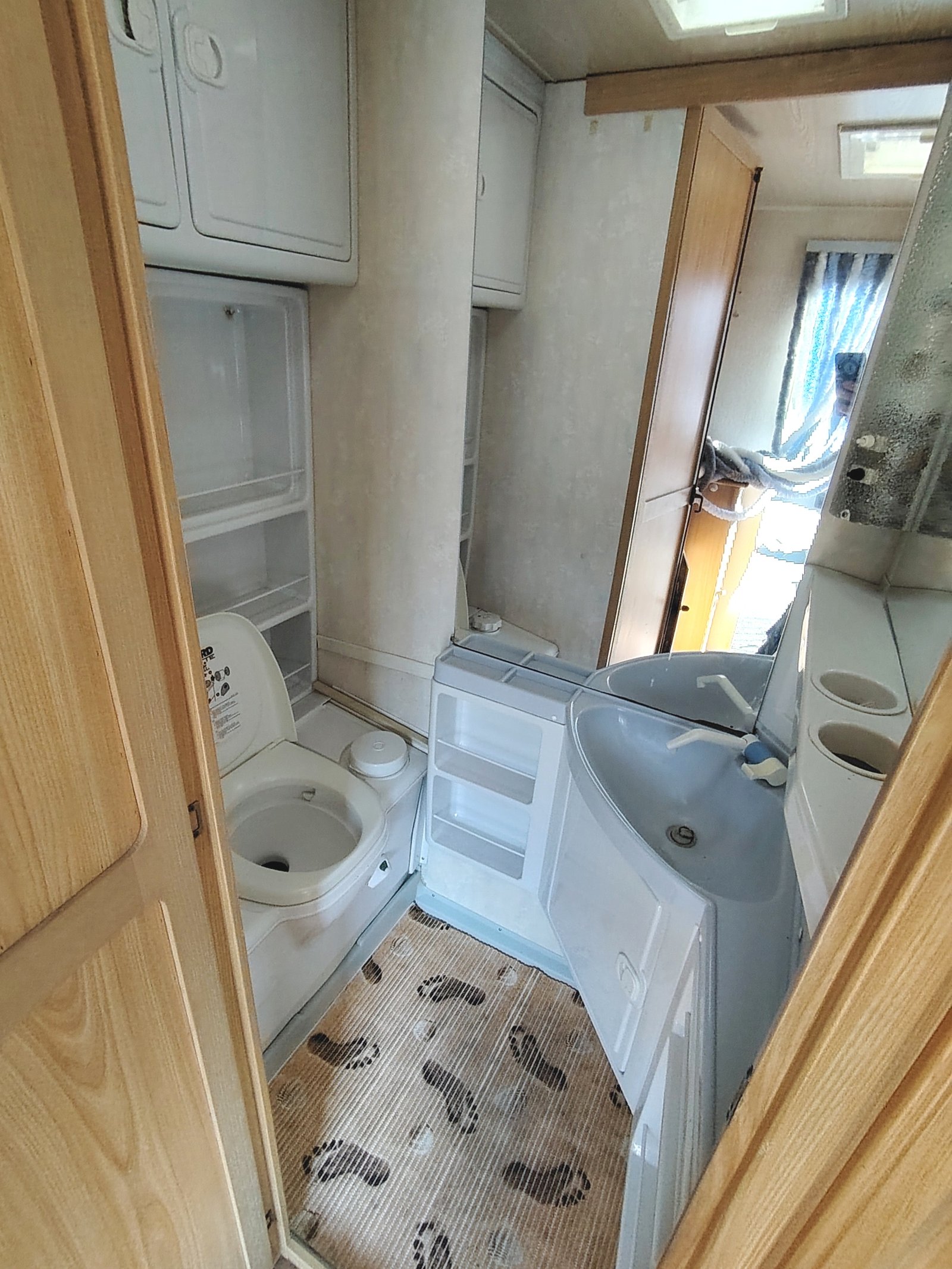 Obrázek interiéru obytného vozu s koupelnou a kuchyňským koutem. Vhodné pro pohodlné cestování.