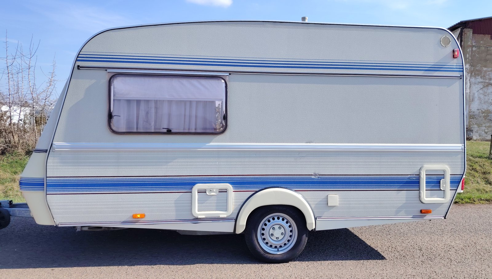 Karavan s modrými pruhy, ideální pro dobrodružné cestování. Perfektní pro rodinné výlety a kempování.