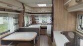 Interiér karavanu s moderním designem, prostorná kuchyň a sedací část pro pohodlné posezení.