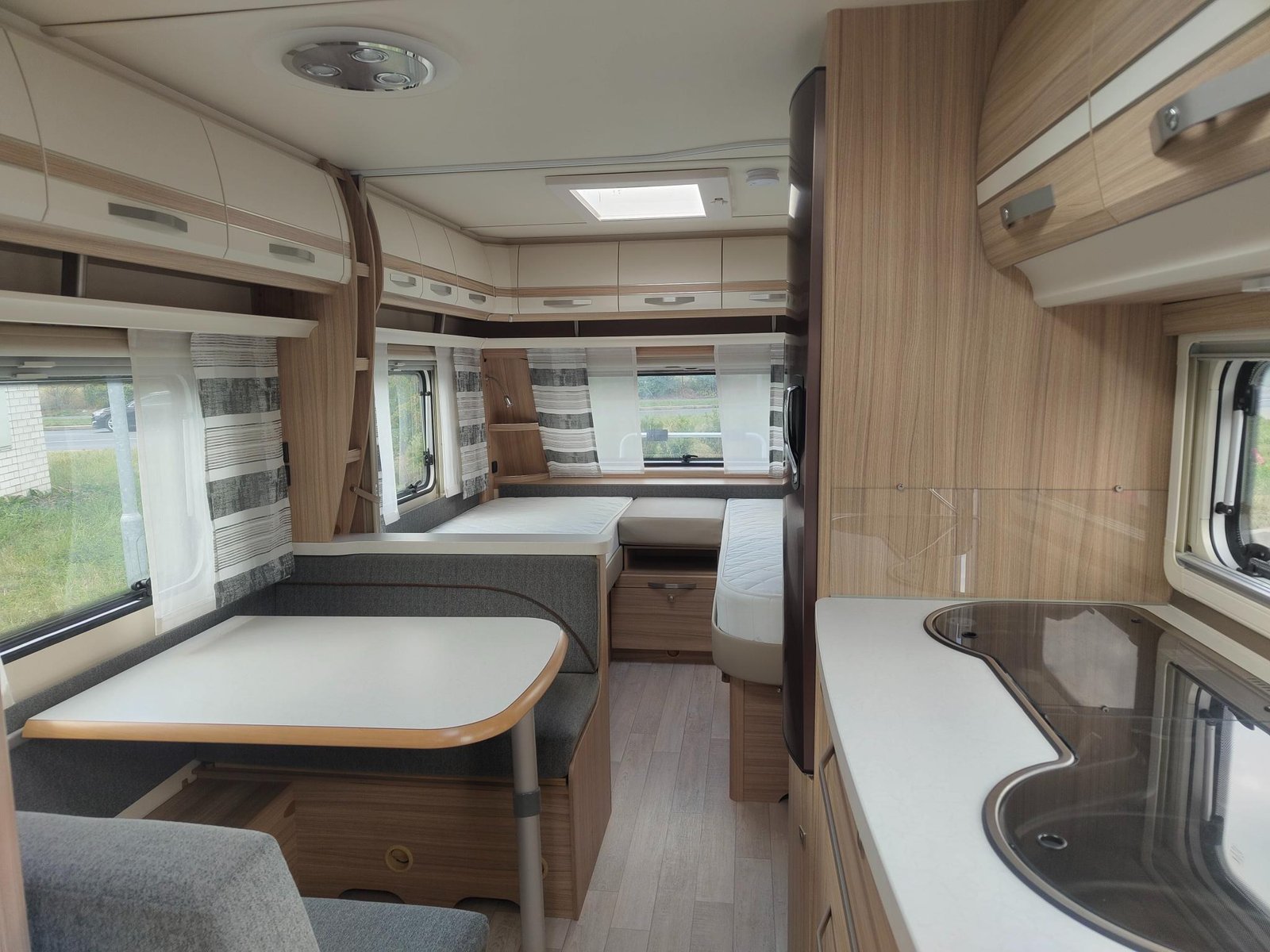 Interiér karavanu s moderním designem, prostorná kuchyň a sedací část pro pohodlné posezení.