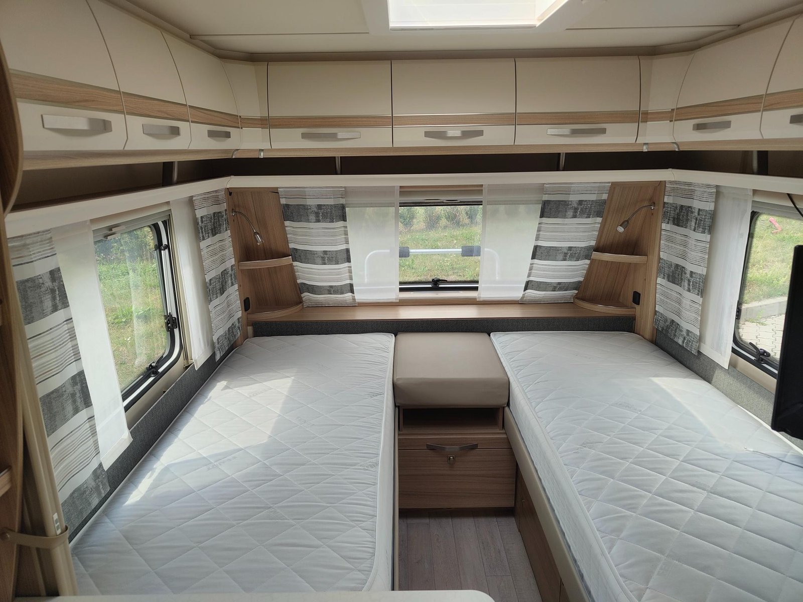 Obrázek interiéru karavanu s pohodlnými lůžky a moderním designem, ideální pro cestování a odpočinek.