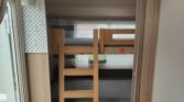 Vnitřní prostor karavanu s patrovými postelemi a moderním designem pro pohodlné cestování.