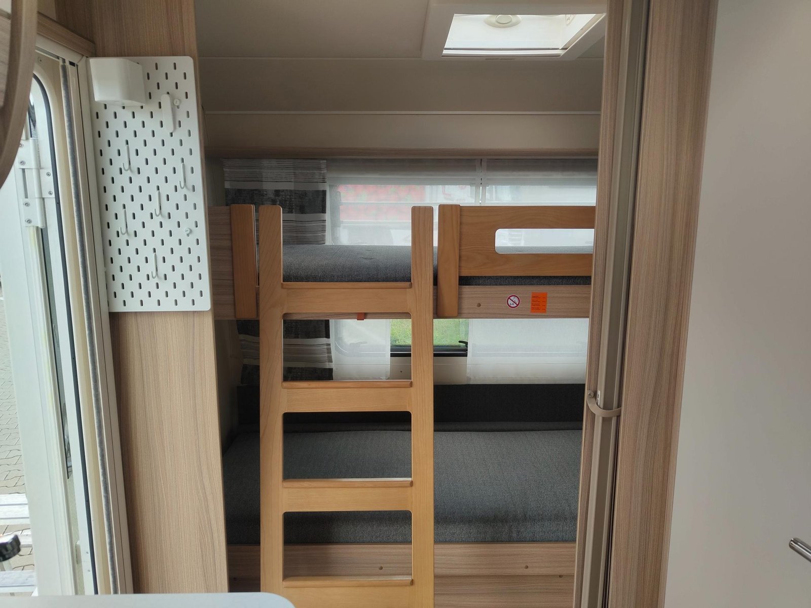 Vnitřní prostor karavanu s patrovými postelemi a moderním designem pro pohodlné cestování.