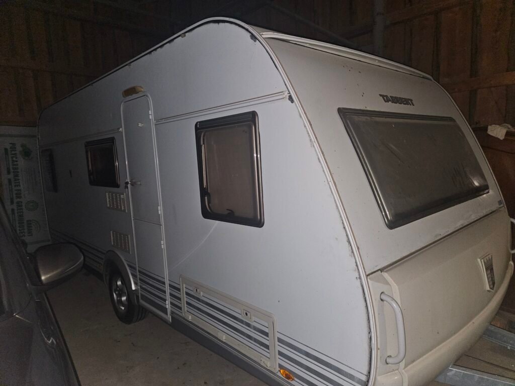 Karavan Tabbert v garáži, zachovalý stav s minimálním poškozením. Ideální pro dobrodružné cesty.