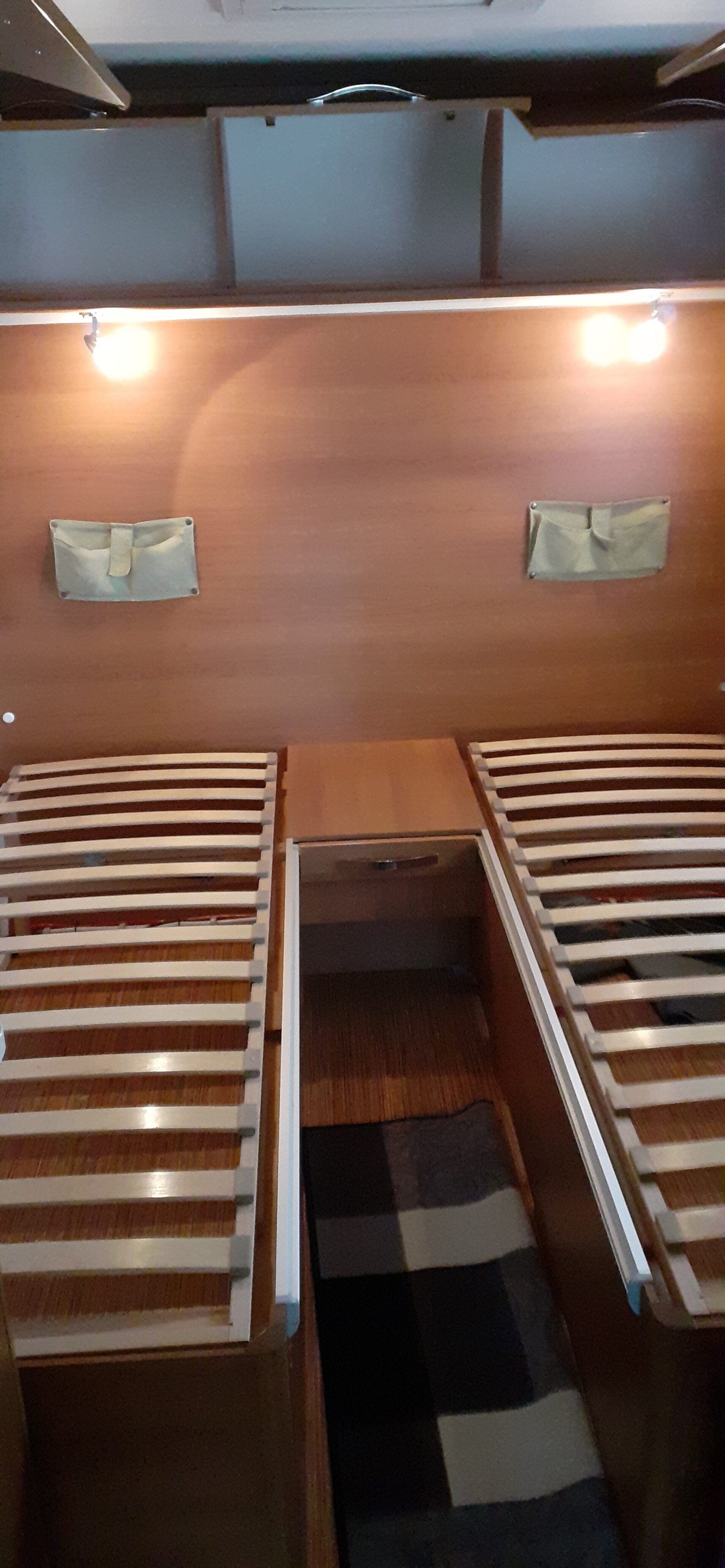 Obrázek interiéru karavanu se skládacími postelemi a úložným prostorem. Příjemný a praktický design pro pohodlné cestování.