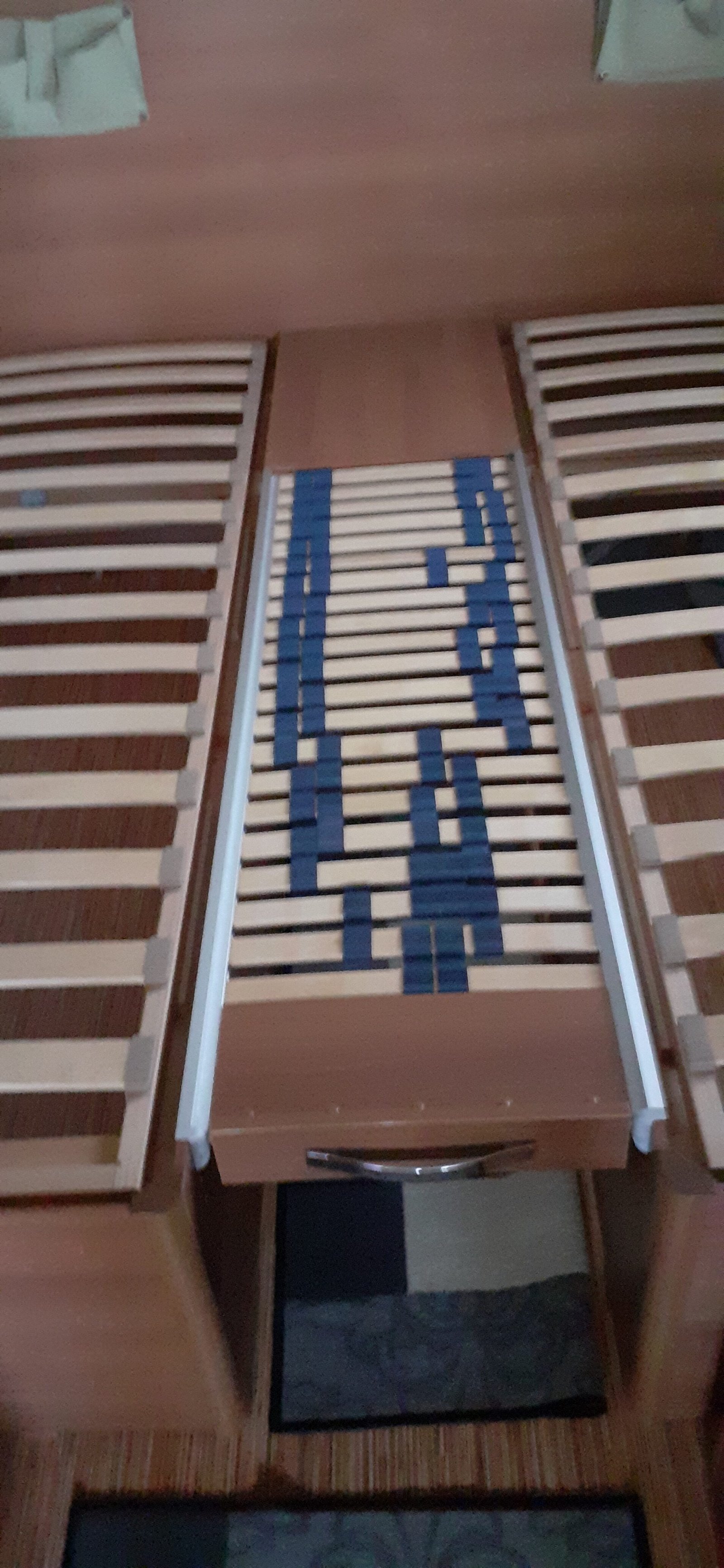 Obrázek ukazuje vnitřek obytného vozu s dřevěnými rošty pro matraci. Komfortní a prostorné uspořádání.