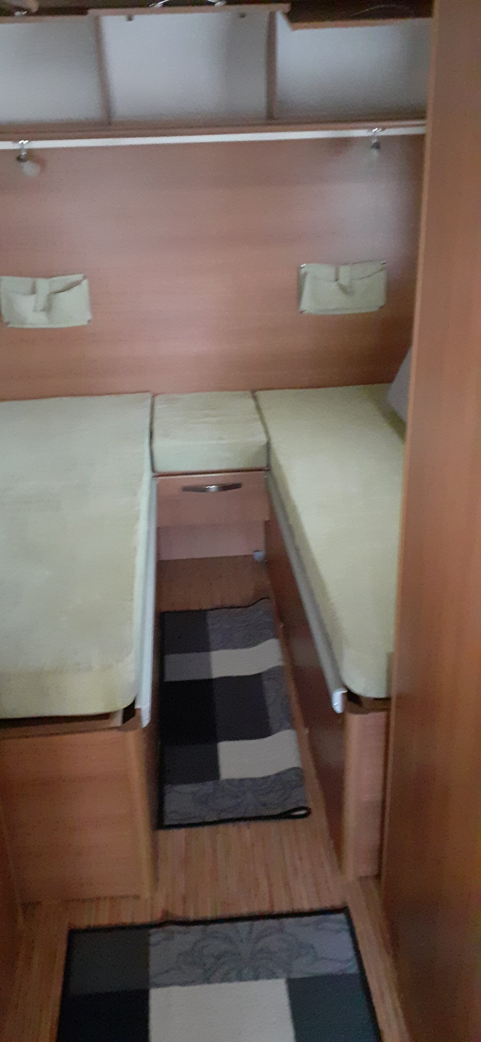 Obrázek interiéru karavanu s dvěma lůžky a úložným prostorem. Příjemné a praktické uspořádání pro pohodlné cestování.