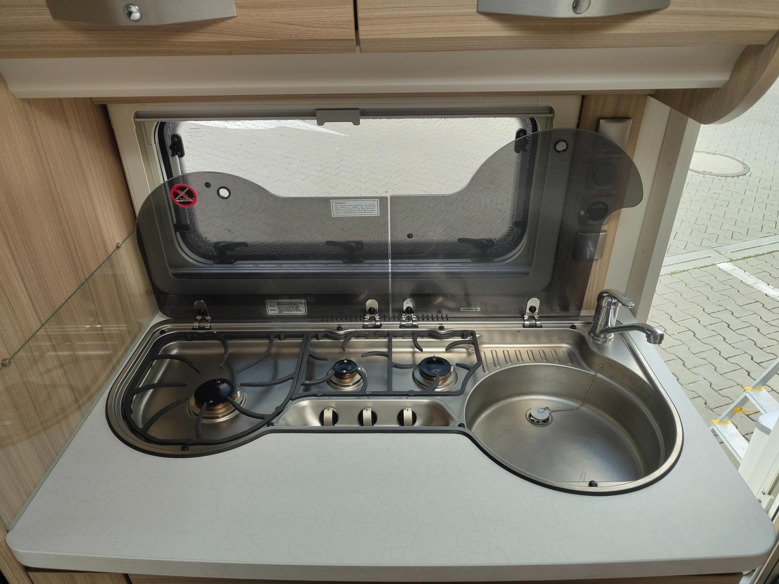 Kuchyňský kout s dvouvařičem a dřezem v obytném autu. Moderní design pro pohodlné vaření na cestách.