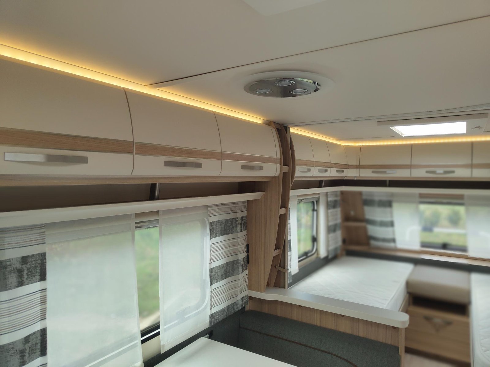 Interiér moderního karavanu s komfortním uspořádáním a příjemným osvětlením.