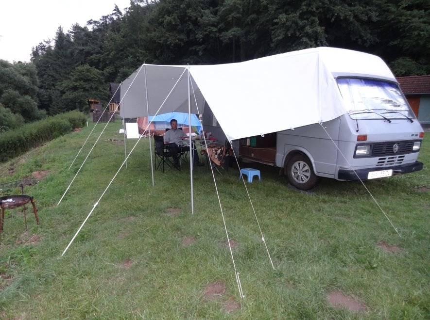 Obytné auto Volkswagen s přístřeškem, pohodlné místo na kempování a relaxaci v přírodě.