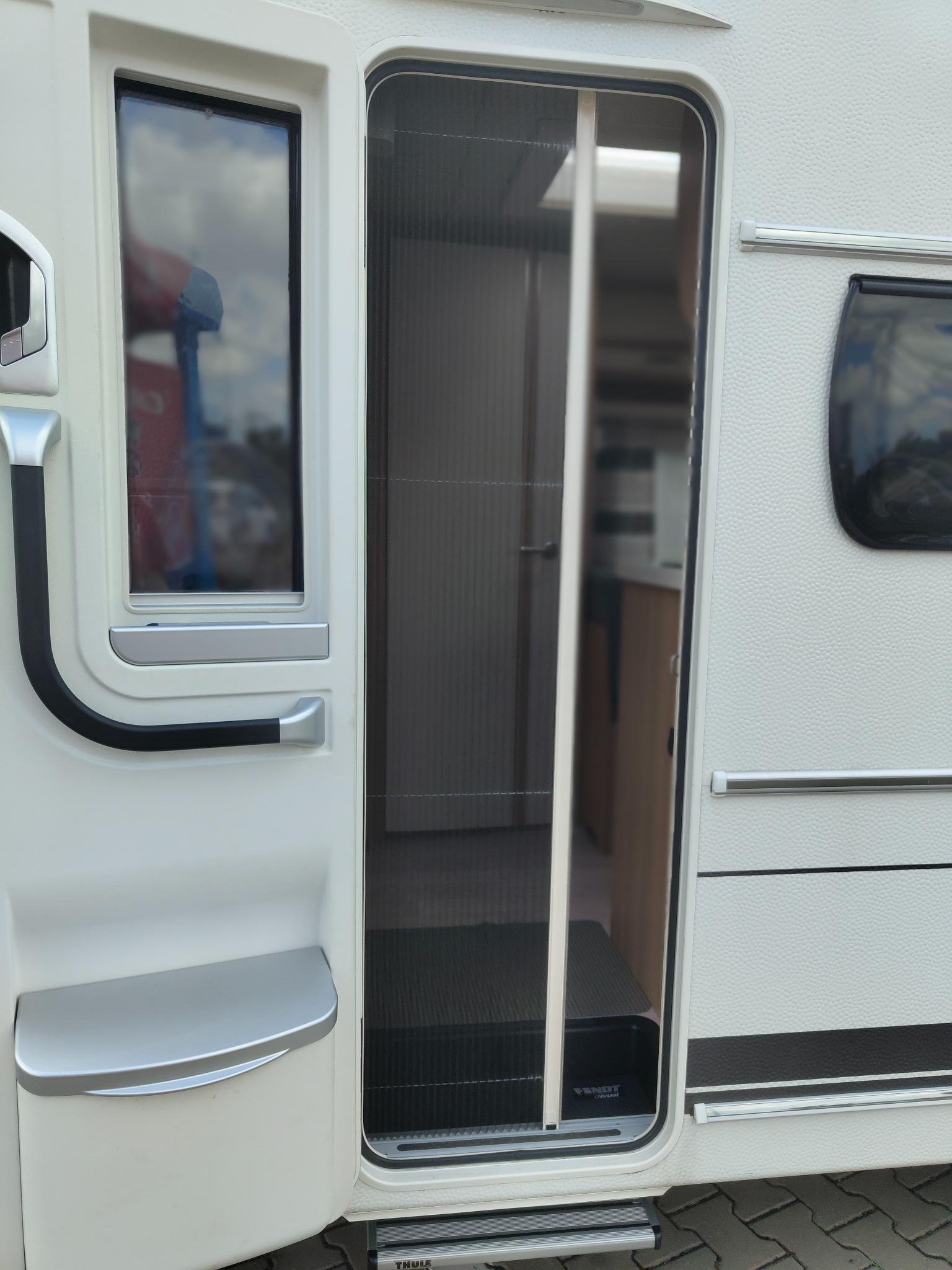 Obrázek ukazuje vstup do karavanu značky Fendt, ideální pro pohodlné cestování a kempování.