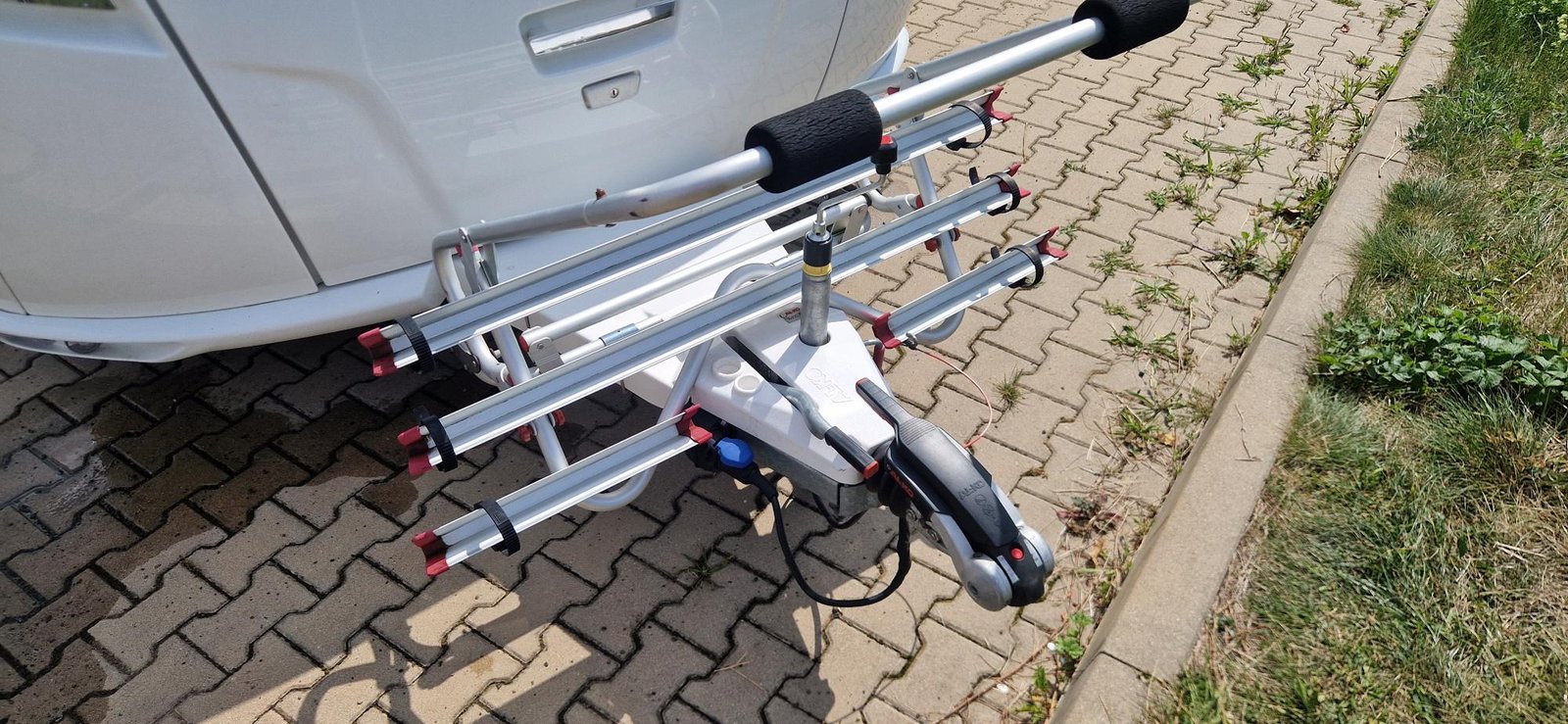 Na obrázku je karavan s připojovacím zařízením a držákem na kola. Detailní pohled na příslušenství.
