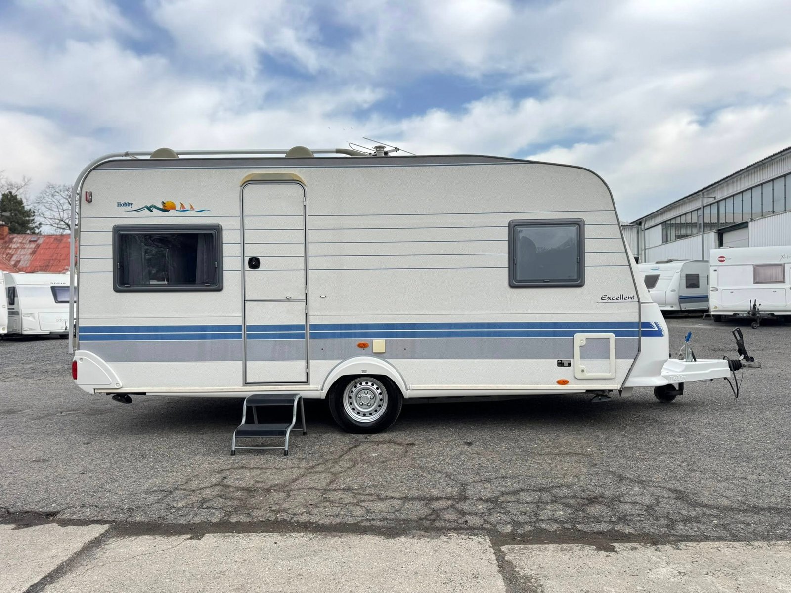 Karavan Hobby Excellent s modrým pruhováním, ideální pro vaše dobrodružství na cestách.