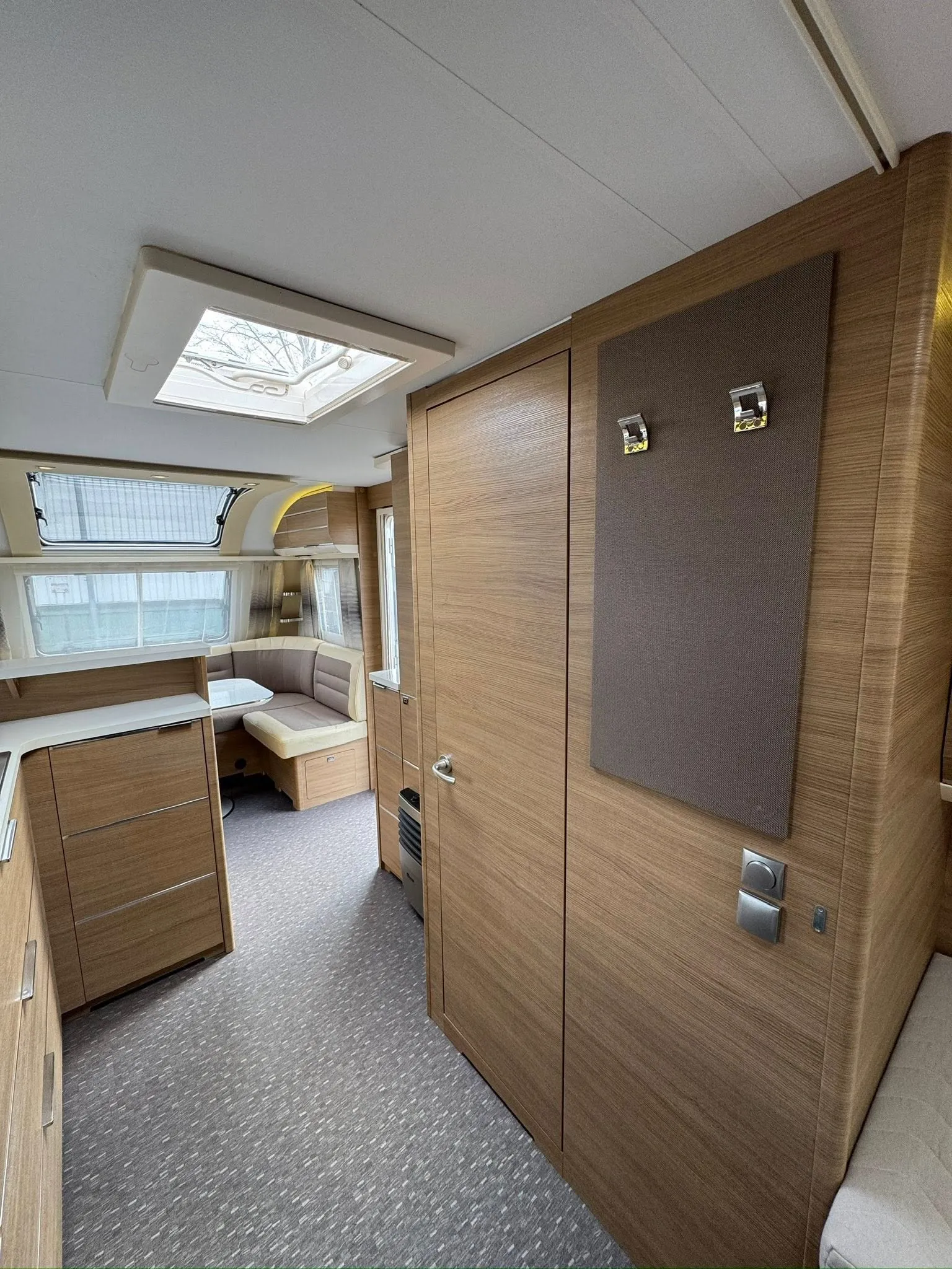 Interiér moderního karavanu s dřevěnými prvky a pohodlným posezením. Ideální pro cestování.