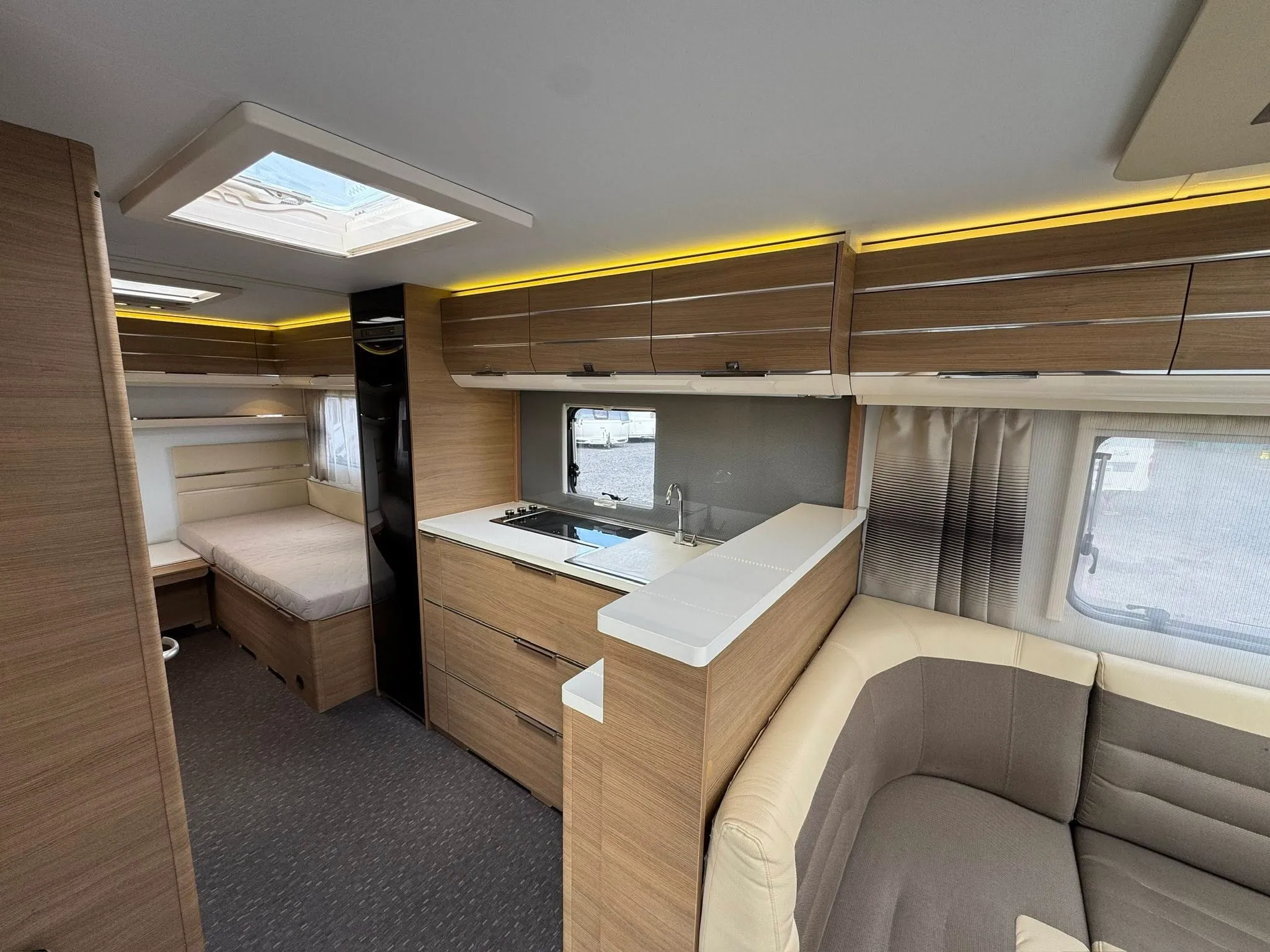 Interiér karavanu s moderním designem a plně vybavenou kuchyní. Ideální pro pohodlné cestování.