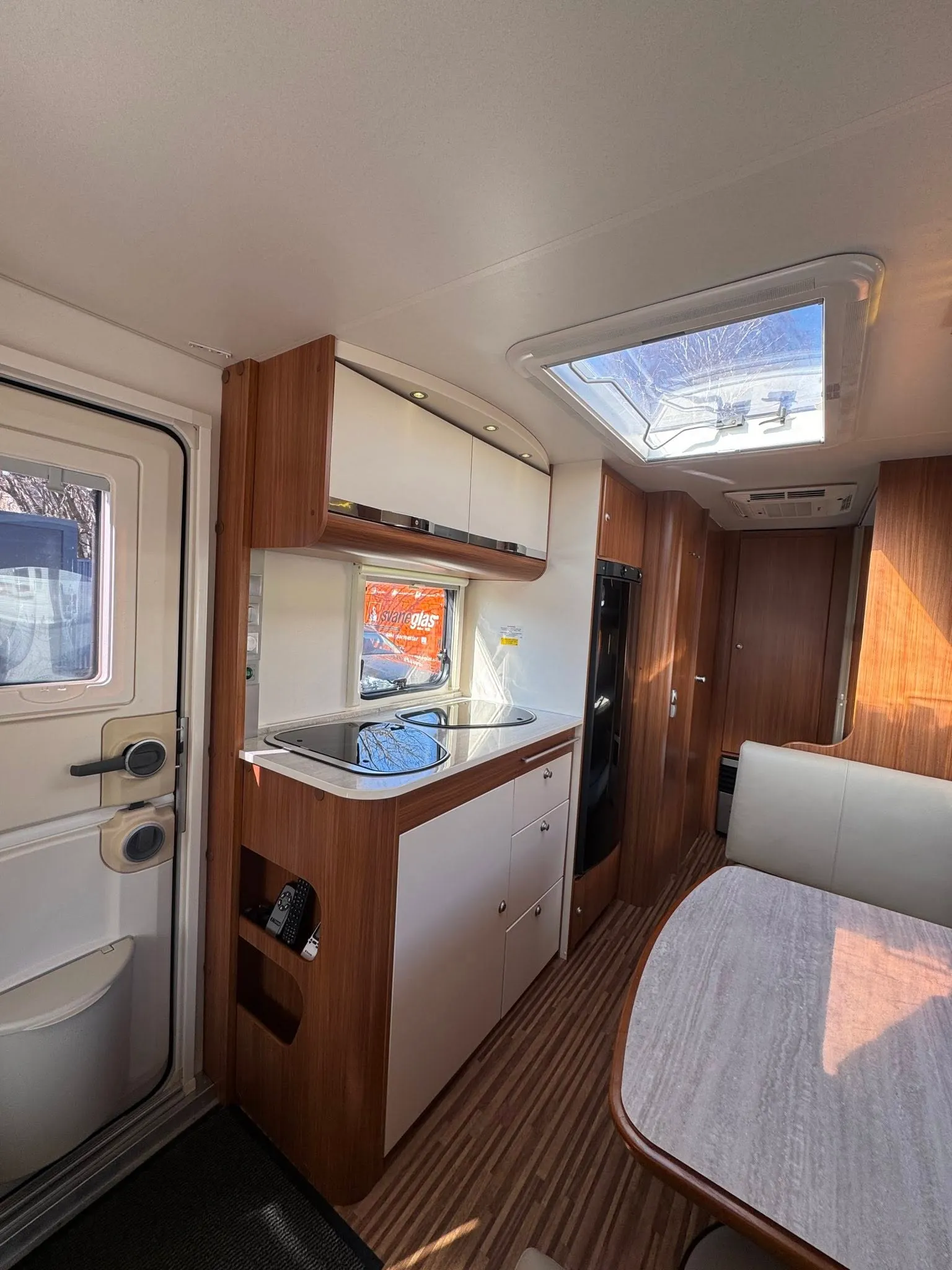 Interiér obytného auta s moderním designem a vybavením, pohodlné posezení a kuchyňský kout.