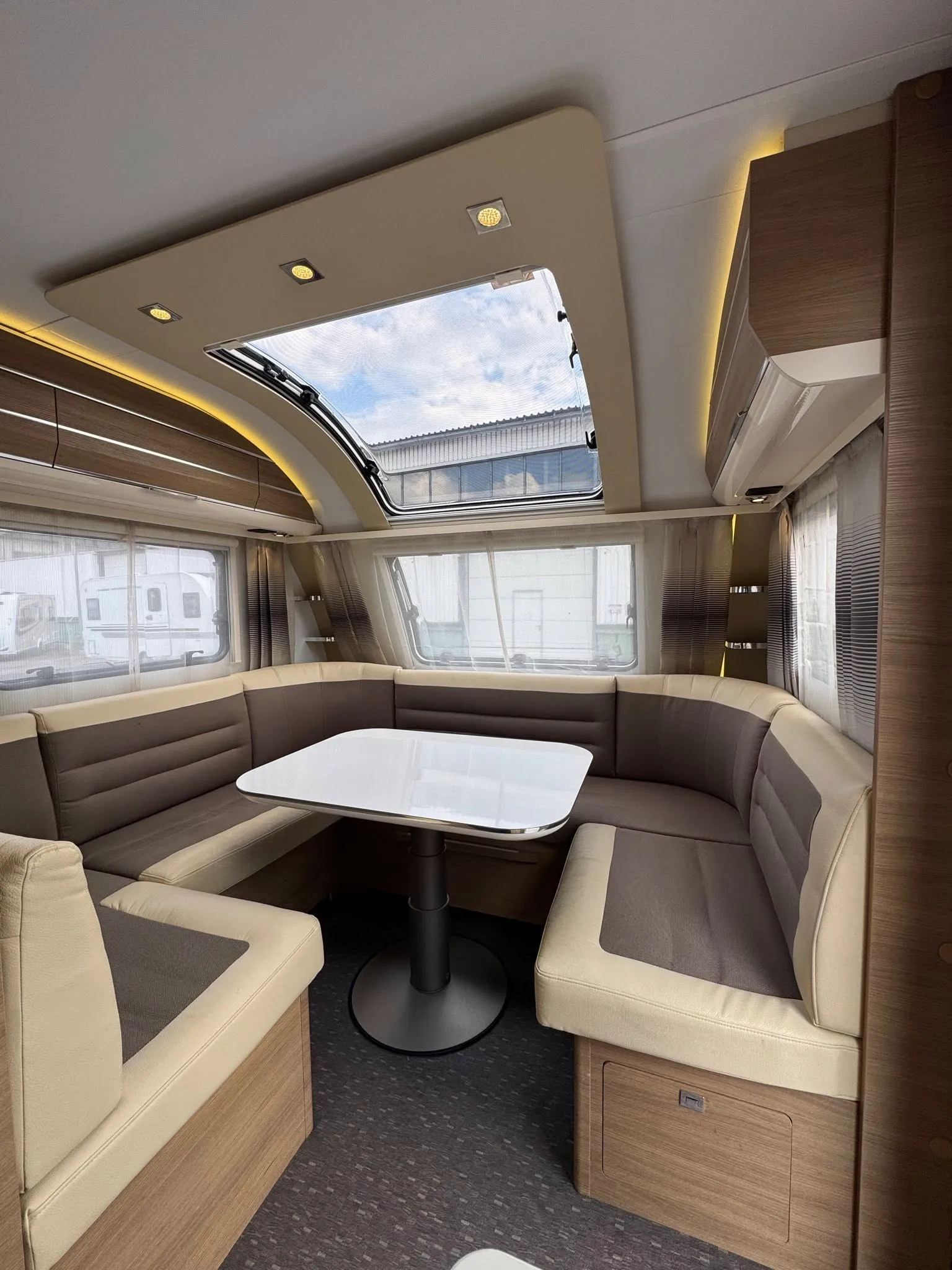 Moderní interiér karavanu s pohodlným sezením a stolkem. Ideální pro rodinné výlety a relaxaci na cestách.