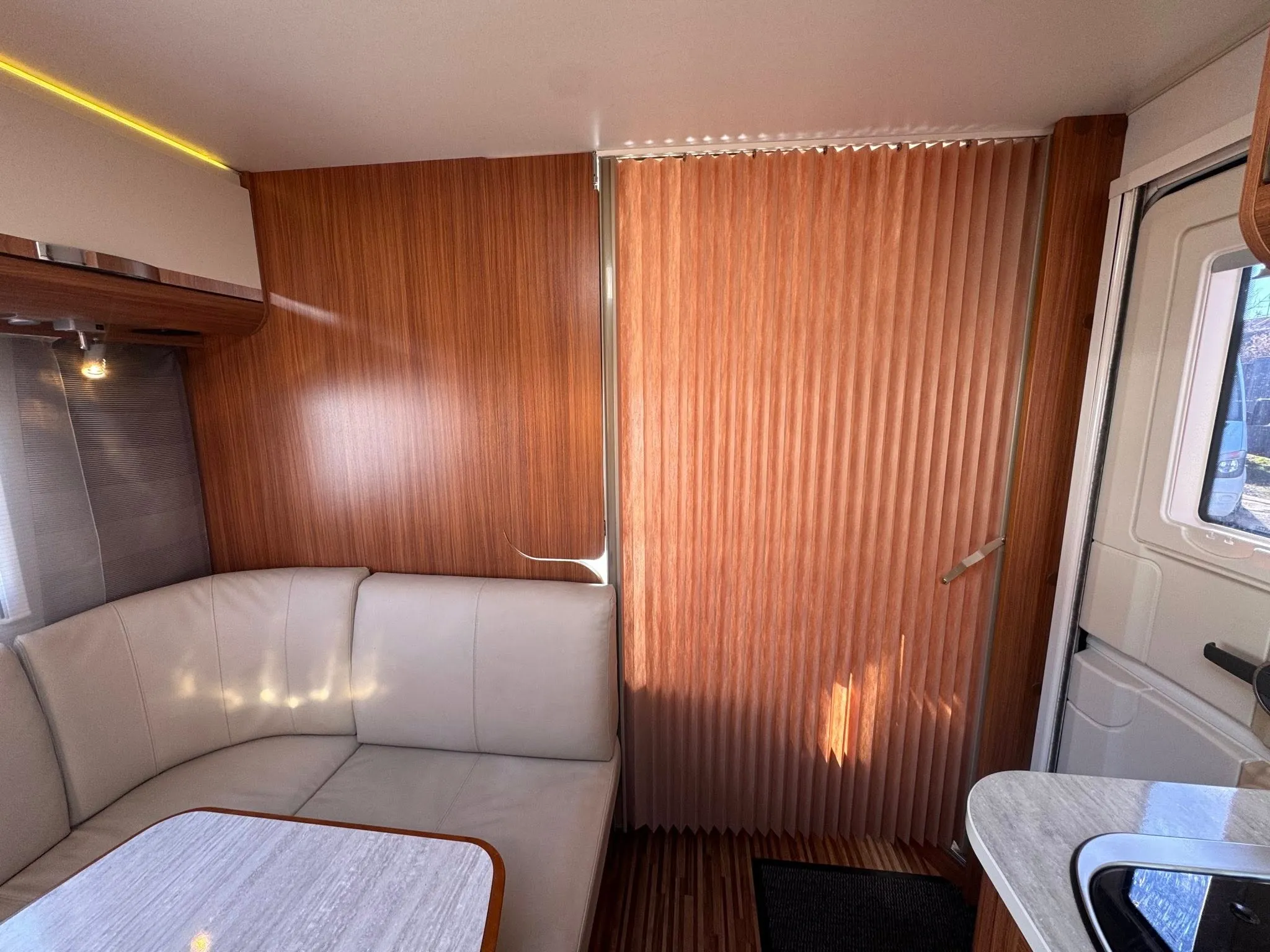 Interiér moderního karavanu s pohodlným sezením a dřevěnými detaily. Ideální pro pohodlné cestování.