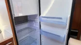 Obrázek zobrazuje interiér obytného vozu s moderní lednicí značky Dometic. Ideální pro kempování a cestování.