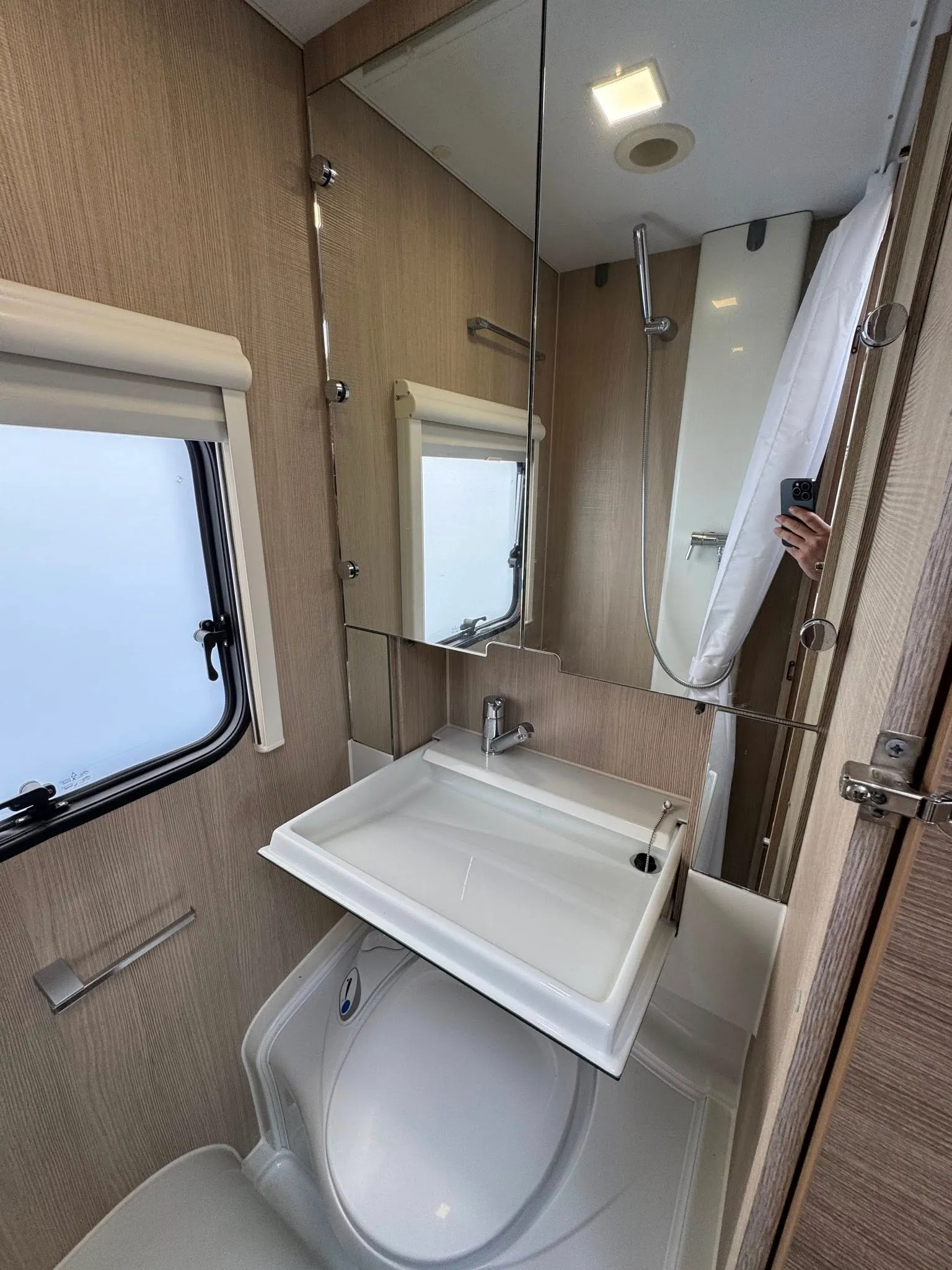Moderní koupelna v karavanu s umyvadlem a sprchovým koutem. Ideální pro komfortní cestování.
