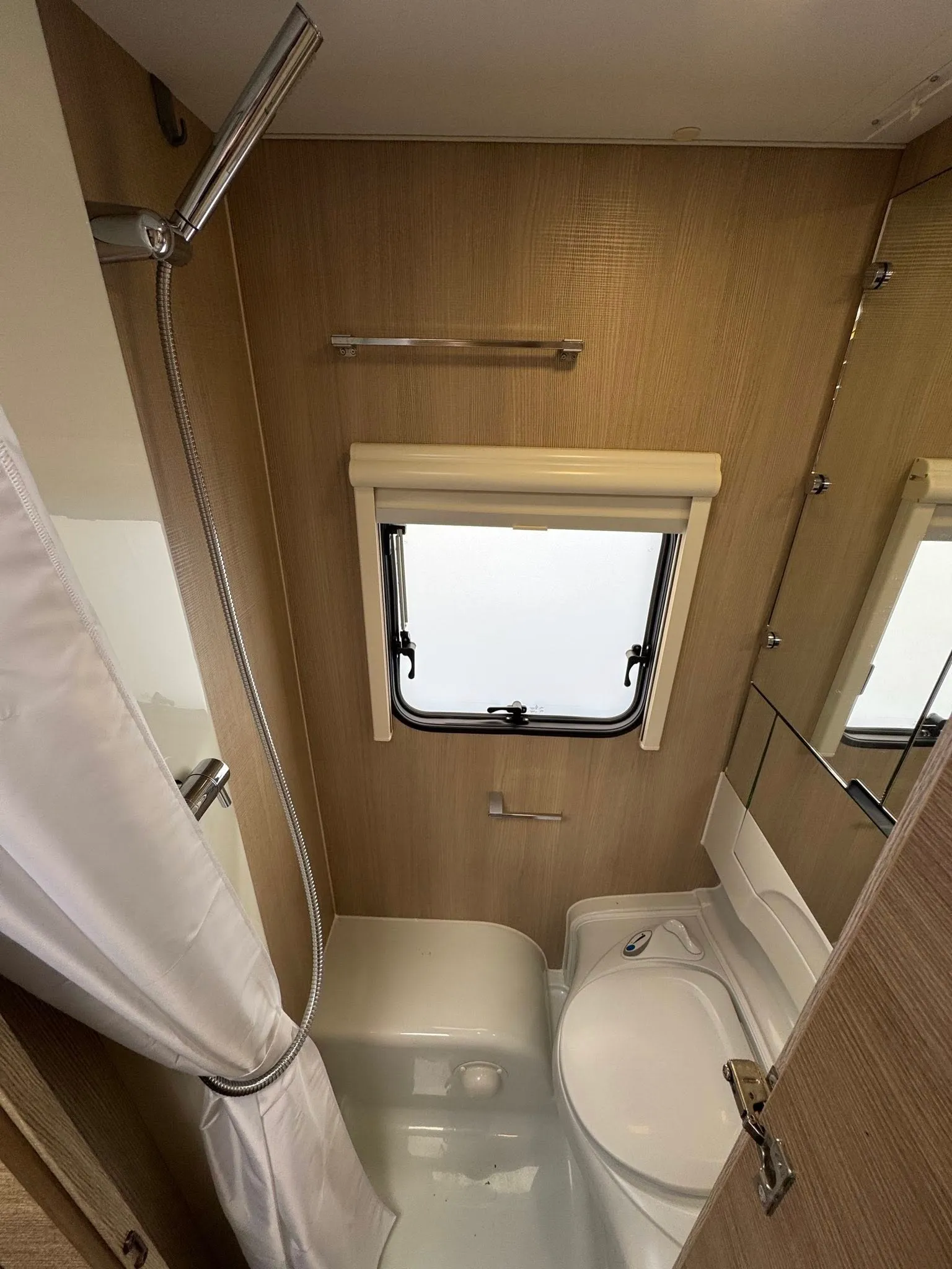 Obrázek ukazuje moderní koupelnu v karavanu s praktickým uspořádáním. Ideální pro pohodlné cestování.