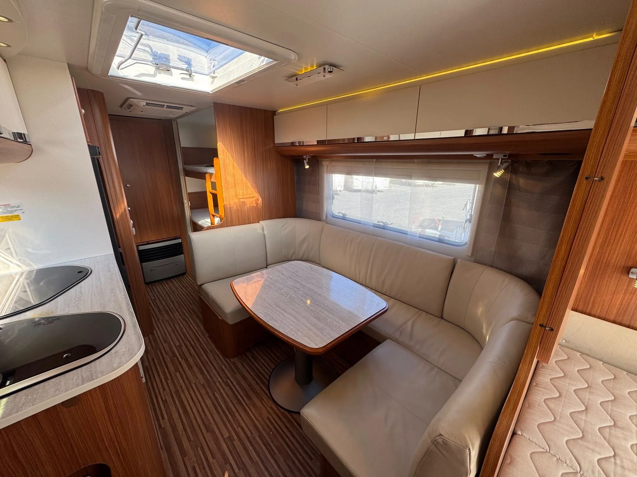 Obrázek interiéru karavanu s pohodlným sezením a stoly, ideální pro rodinné výlety.