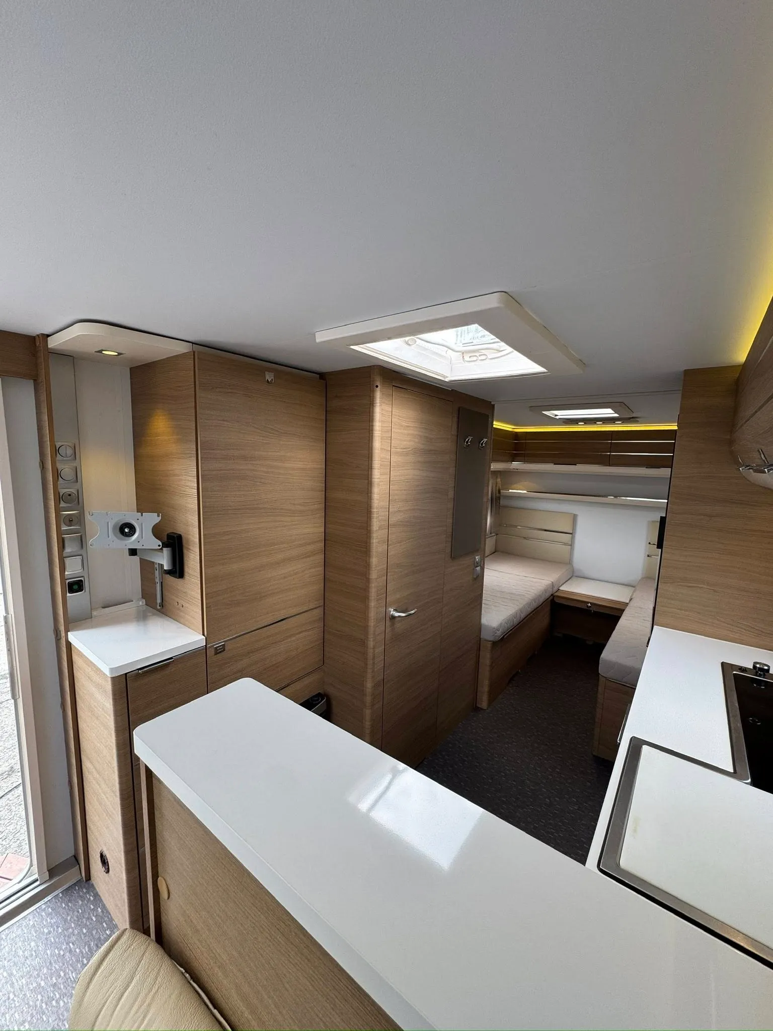 Moderní interiér obytného auta s dřevěnými prvky a pohodlným rozložením pro bydlení. Ideální pro dobrodružství.