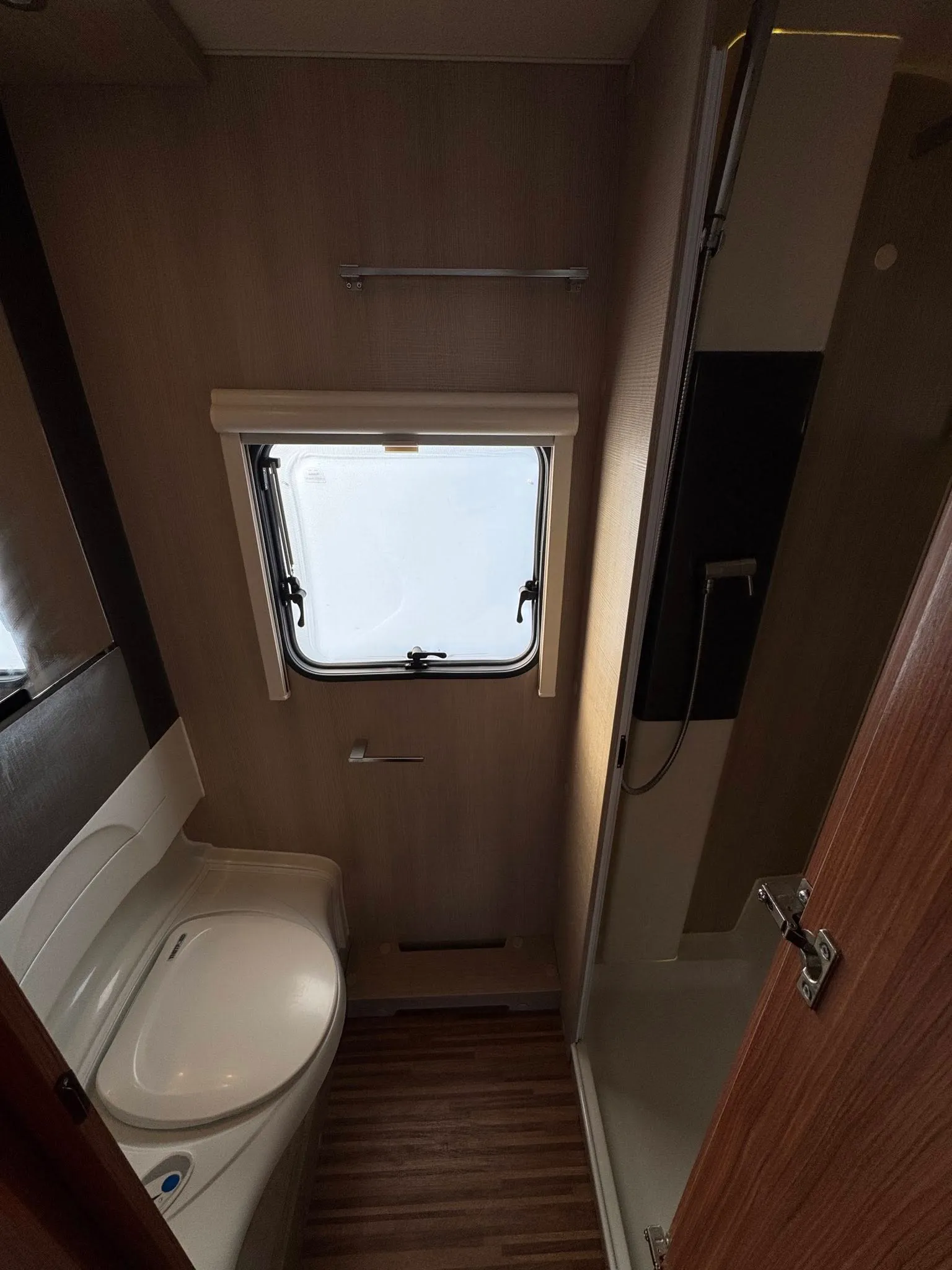 Obrázek interiéru karavanu s koupelnou a sprchou. Moderní design a praktické řešení prostoru.