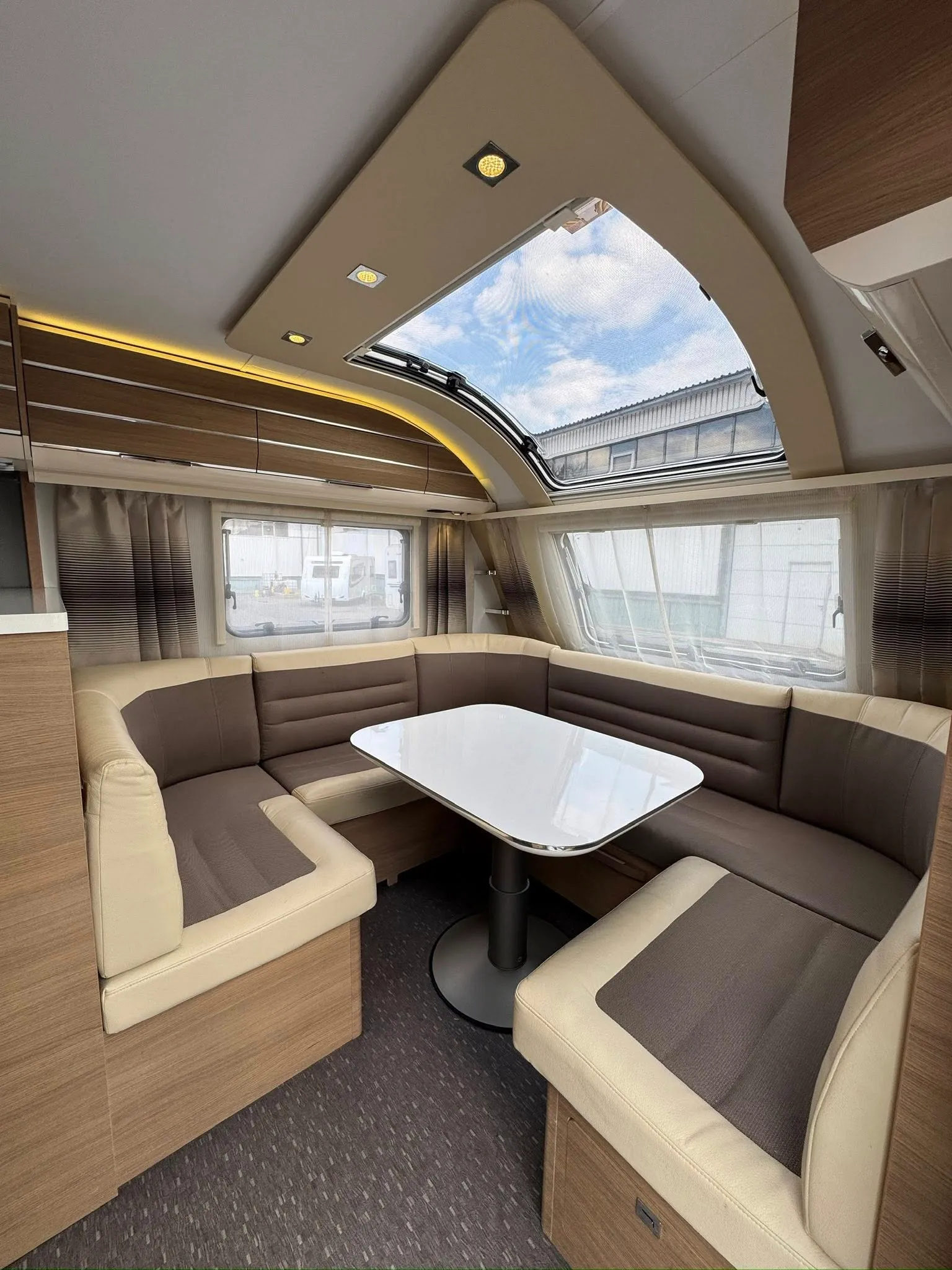 Moderní karavan s pohodlným sezením a velkým oknem, ideální pro útulné cestování.