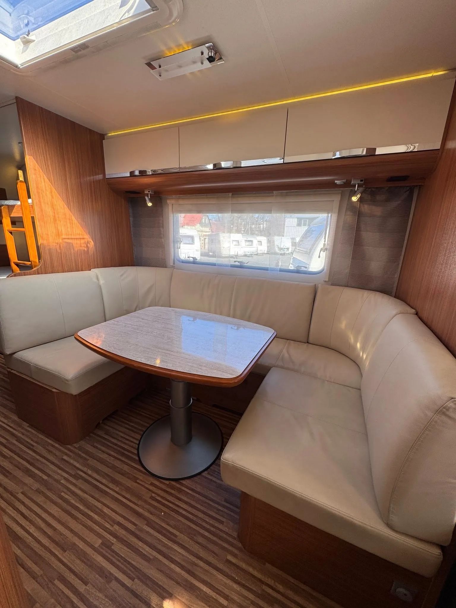 Interiér karavanu s pohodlným posezením a stolem. Praktický prostor pro odpočinek a relaxaci na cestách.