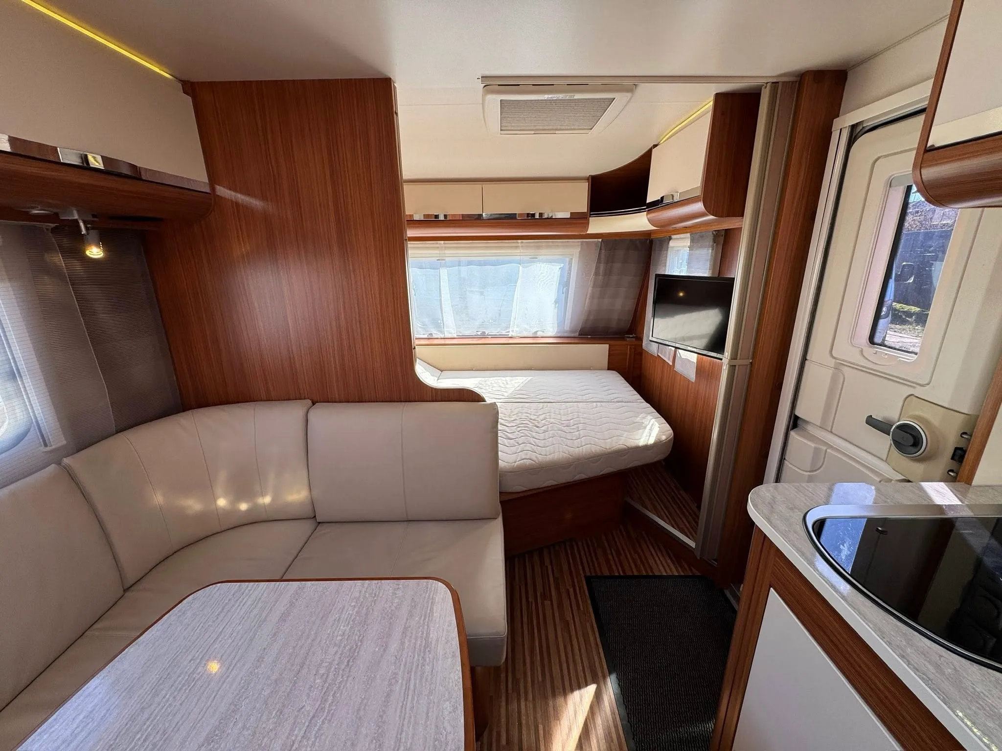 Karavan s moderním interiérem, vybavený pohodlným posezením a kuchyňským koutem. Ideální pro dobrodružství na cestách.