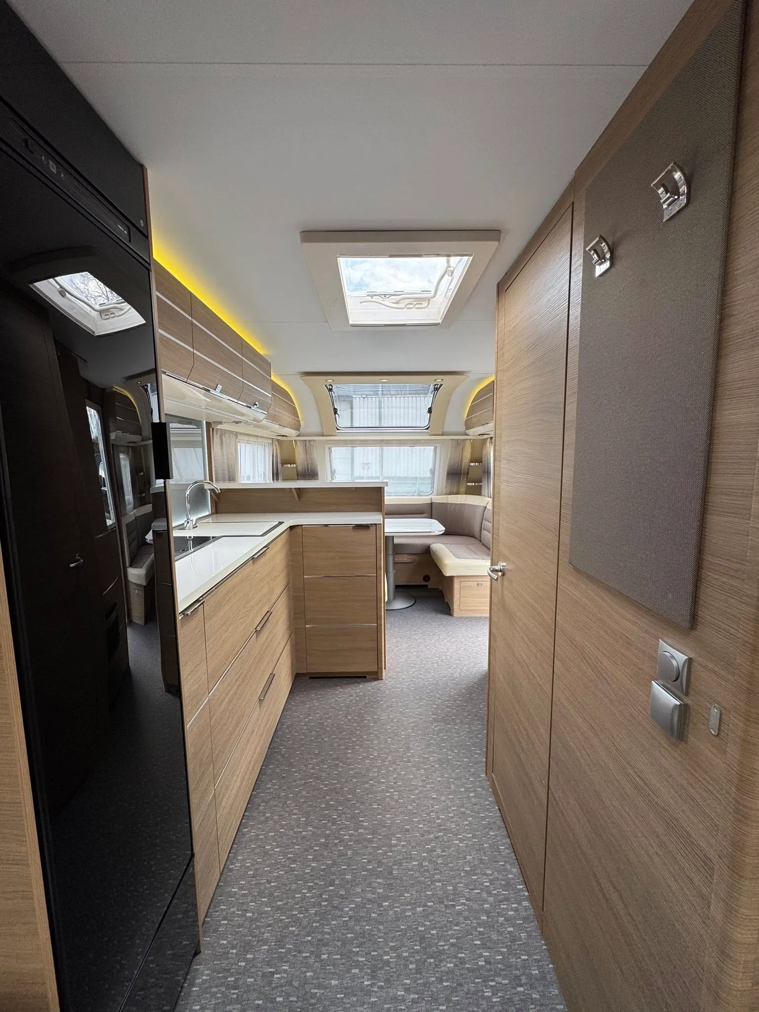 Moderní interiér karavanu s kuchyní a obytnou částí, zaměřený na komfort a design. Ideální pro cestování.