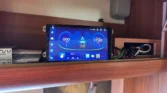 Obrázek ukazuje moderní palubní systém v obytném autě, s digitálním displejem a připojením pro hudbu.