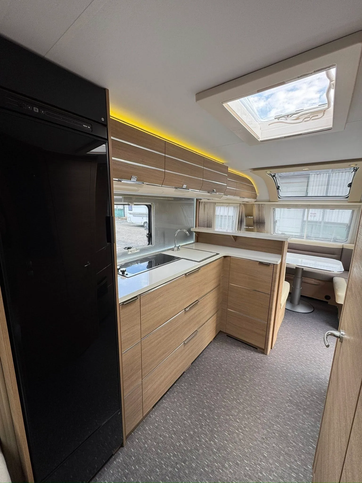 Moderní karavan s prostornou kuchyňkou a příjemným interiérem, ideální pro pohodlné cestování.