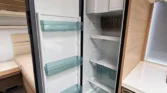 Obrázek zobrazuje interiér karavanu s velkým lednicí. Moderní design a funkční uspořádání pro komfortní cestování.