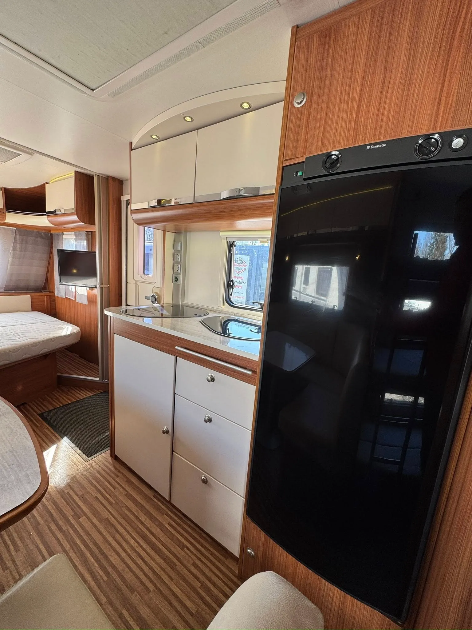 Obrázek interiéru karavanu s moderními spotřebiči a dřevěným dekorem. Komfortní prostředí pro cestování.