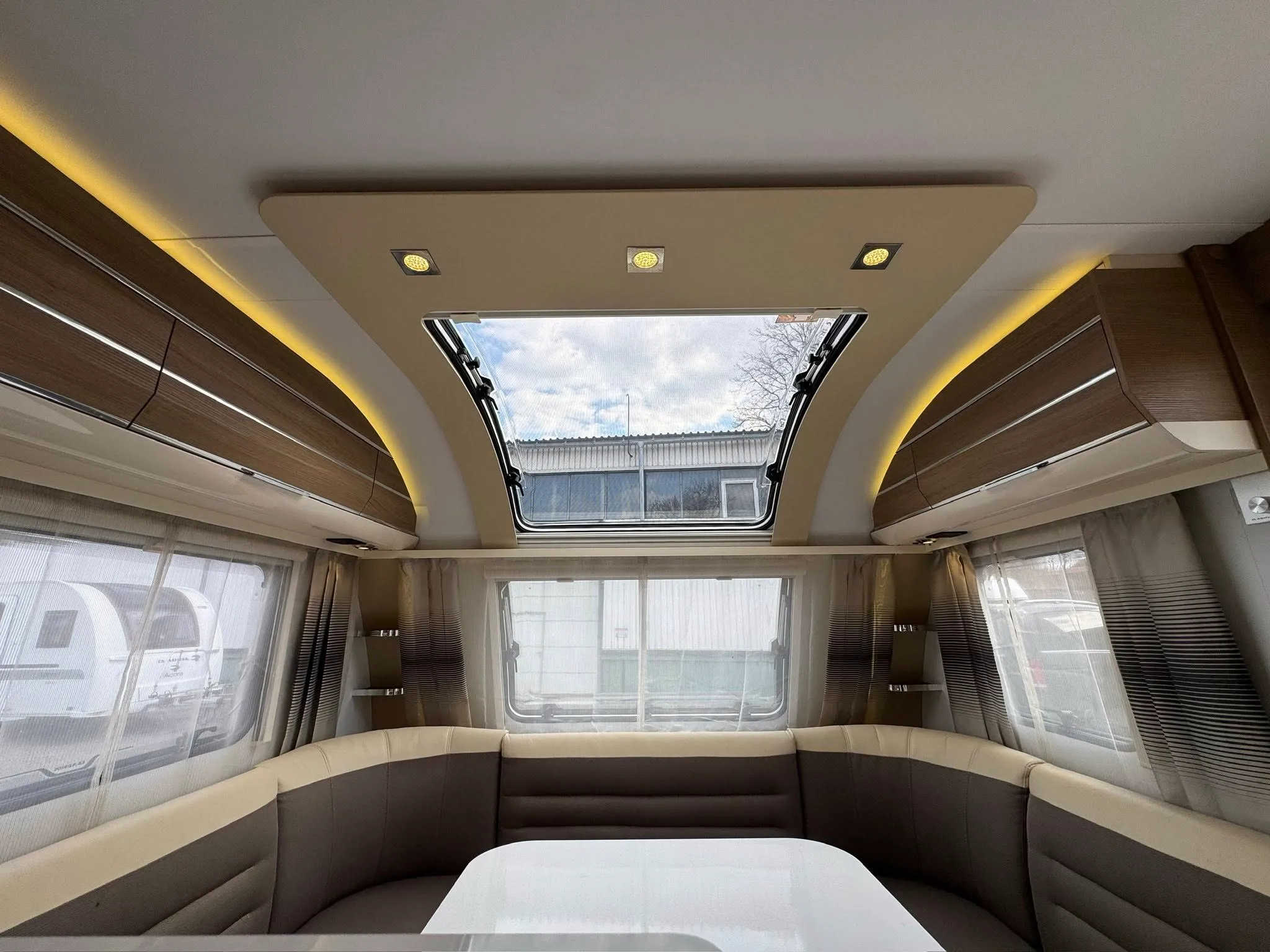 Interiér moderního karavanu s panoramatickým oknem a pohodlným sezením. Ideální pro kempování a cestování.