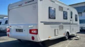 Karavan Adria Adora na slunném parkovišti, s elegantním designem a prostorným interiérem. Ideální pro dobrodružství!
