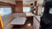 Interiér karavanu s pohodlným sezením a kuchyňkou, ideální pro cestování a relaxaci.